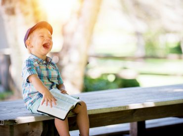boy sitting on bench while holding a book