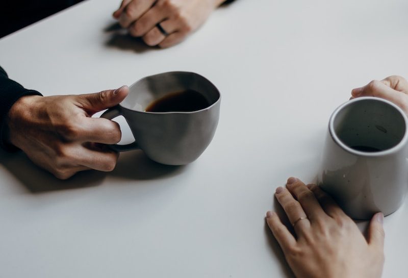 a couple of people sitting at a table with cups of coffee