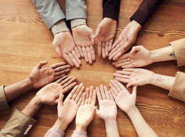 Photo Of People's Hand On Top Of Wooden Table