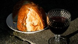 Bread and wine on a textured stone surface.