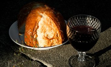 Bread and wine on a textured stone surface.