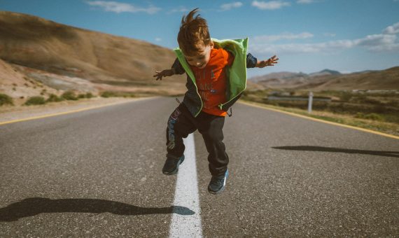 a young boy is jumping in the air on a road