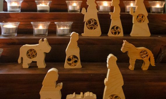 a set of wooden nativity figurines with candles in the background
