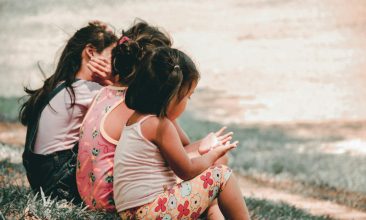 three children sitting on grass