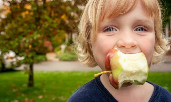 Young child with a bitten apple in mouth
