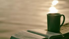 green ceramic mug beside book