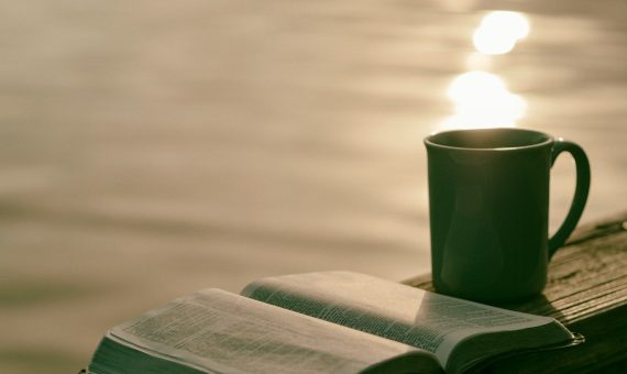 green ceramic mug beside book