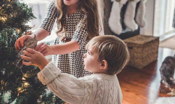 boy and girl decorating Christmas tree inside room