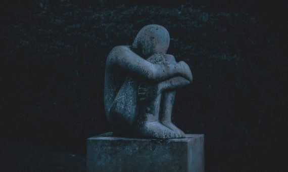 man hugging his knee statue