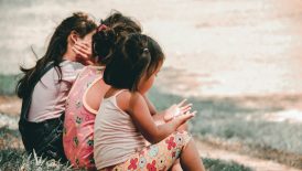 three children sitting on grass